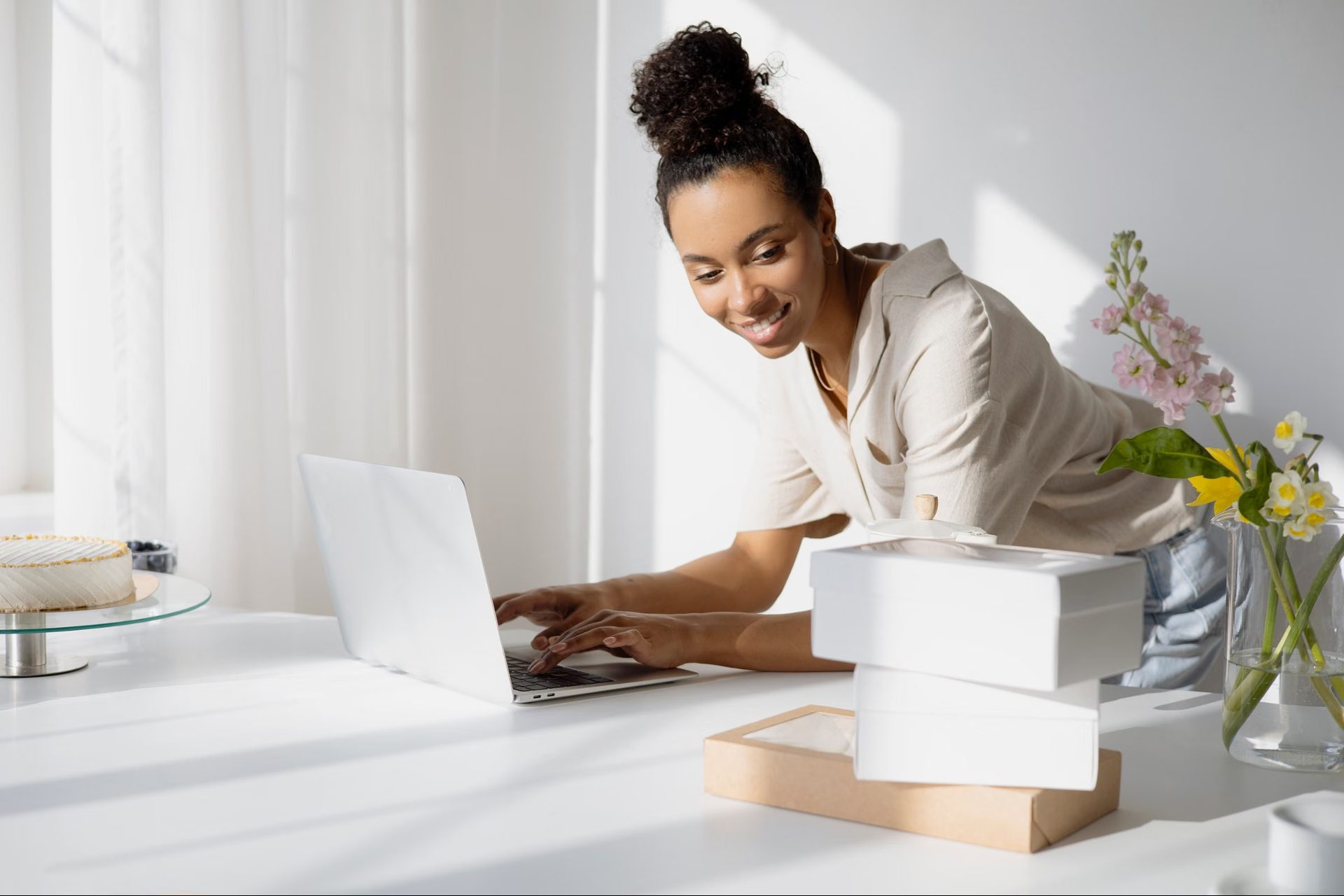 A business owner smiling while working on a laptop in a bright studio